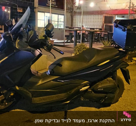 קטנוע שחור עם ארגז אחורי חונה ברחוב בלילה
